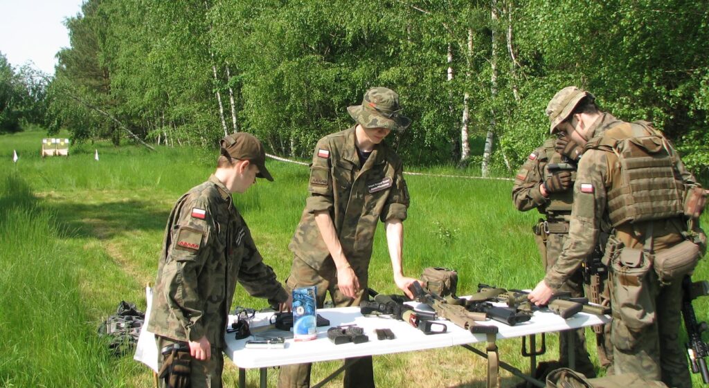 Na zdjęciu grupa członków JS 2083 rozkładająca sprzęt wojskowy na stoliku. 