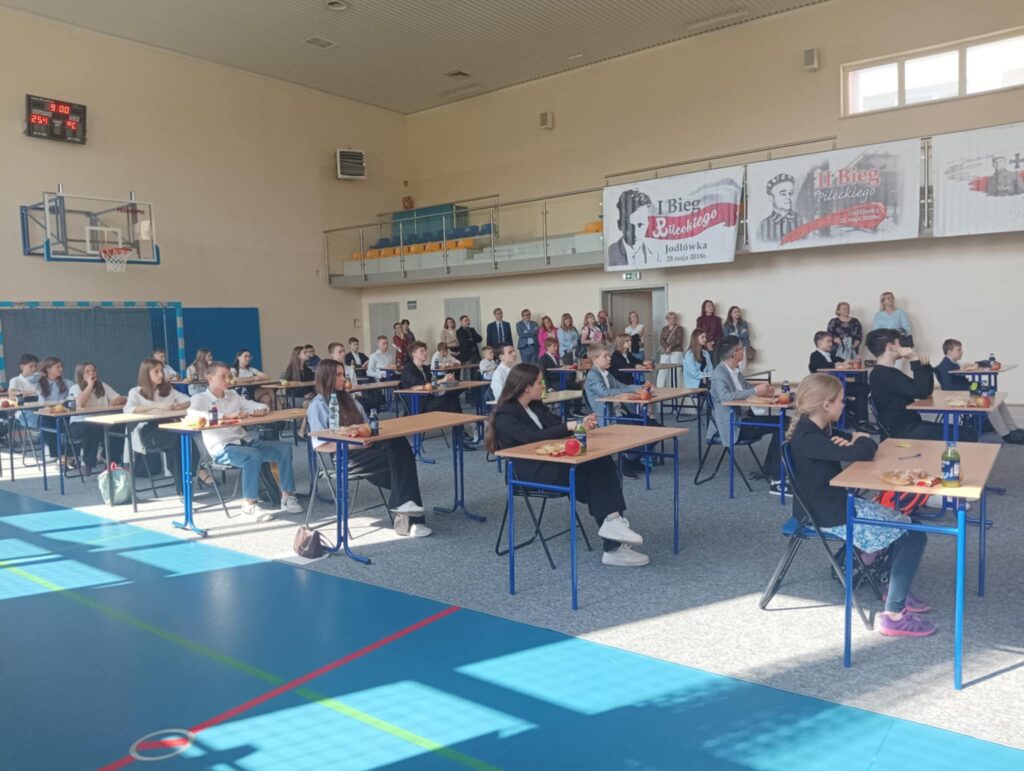 Na zdjęciu sala gimnastyczna i uczestnicy konkursu siedzący przy stolikach