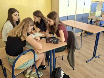 Grupa uczennic siedząca i pracująca przy stoliku