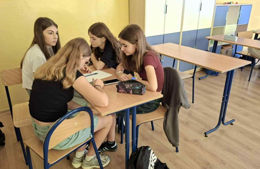 Grupa uczennic siedząca i pracująca przy stoliku