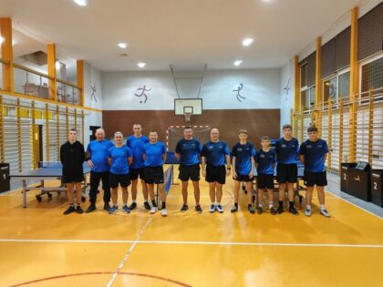 Grupa graczy obu drużyn w sali gimnastycznej