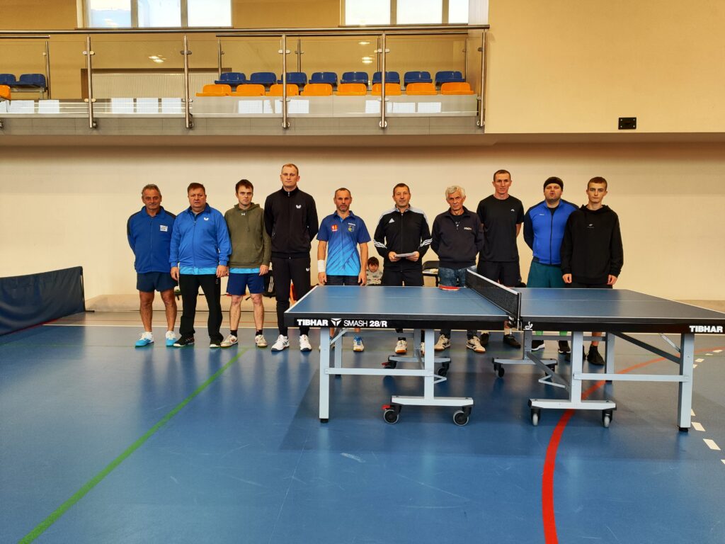 Dwie drużyny tenisa stołowego stojące przy stole do ping-ponga. 
