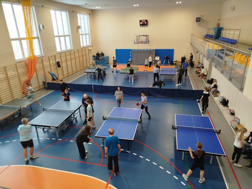 Zdjęcie z góry na halę z rozstawionymi stołami do tenisa i graczami