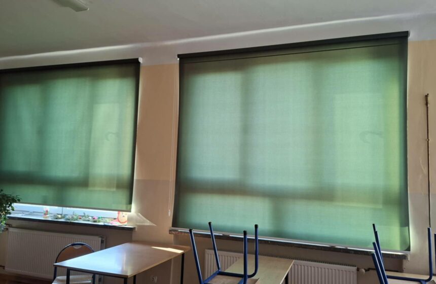 Zdjęcie dwóch okien z zielonymi roletami