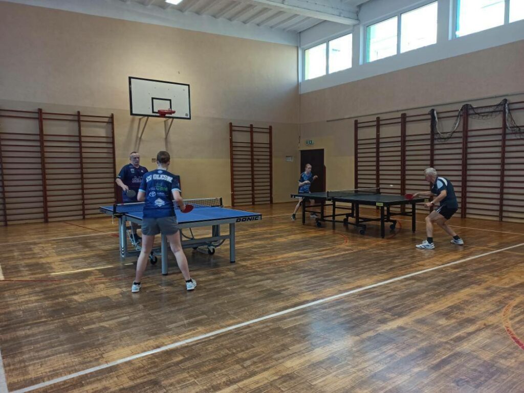 Dwie pary tenisistów podczas gry w tenisa stołowego.