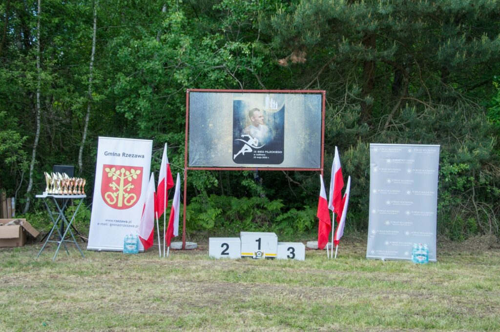 Podium na tle baneru z logo biegu i flag Polski